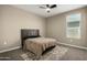 Bedroom with a black headboard, ceiling fan, window and light carpet at 37783 W San Sisto Ave, Maricopa, AZ 85138