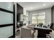 Modern home office featuring frosted sliding glass doors, dark wood desk, and two guest chairs at 37783 W San Sisto Ave, Maricopa, AZ 85138