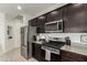 Close up of kitchen with stainless steel appliances, granite countertops, and dark wood cabinets at 37783 W San Sisto Ave, Maricopa, AZ 85138