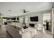 Open-concept living room featuring tile floors, neutral walls, plush sectional, and a kitchen with dark cabinetry at 37783 W San Sisto Ave, Maricopa, AZ 85138