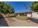 Spacious backyard featuring gravel, turf, and shade trees with an enclosed patio at 3901 W Davidson Ln, Phoenix, AZ 85051