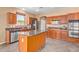 Open kitchen with an island, stainless steel appliances, and wood cabinetry at 41800 W Chambers Ct, Maricopa, AZ 85138