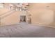 Spacious carpeted living room with stair access and access to an adjacent room through an archway at 41800 W Chambers Ct, Maricopa, AZ 85138