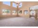 Bright living room featuring soaring ceilings, a ceiling fan, and large windows for natural light at 41800 W Chambers Ct, Maricopa, AZ 85138