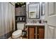 Bathroom with a sink, dark wood cabinets, toilet, and decorative wall shelves at 44715 W Paitilla Ln, Maricopa, AZ 85139