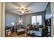 Bedroom with a ceiling fan, chair with ottoman, large desk, and wood floors at 44715 W Paitilla Ln, Maricopa, AZ 85139