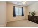 Bright bedroom with neutral carpet, dresser, and sunlit window with navy curtains at 549 W Sweet Shrub Ave, Queen Creek, AZ 85140