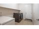 Clean laundry room featuring modern washer and dryer with shelving and door to exterior at 549 W Sweet Shrub Ave, Queen Creek, AZ 85140