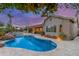 Backyard view featuring pool, spa, covered patio, outdoor kitchen and desert landscaping at dusk at 6751 S Callaway Dr, Chandler, AZ 85249