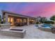 Backyard view featuring pool, spa, covered patio, outdoor kitchen and desert landscaping at dusk at 6751 S Callaway Dr, Chandler, AZ 85249