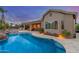 Backyard view featuring pool, spa, covered patio, outdoor kitchen and desert landscaping at dusk at 6751 S Callaway Dr, Chandler, AZ 85249