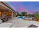 Backyard view featuring pool, spa, covered patio, kitchen and desert landscaping at dusk at 6751 S Callaway Dr, Chandler, AZ 85249