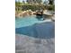 Beautiful pool with rock waterfall feature, lush greenery, and elegant stone border at 6751 S Callaway Dr, Chandler, AZ 85249