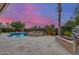 Backyard with a beautiful pool, hot tub, stone waterfall, and lush landscaping at dusk at 6751 S Callaway Dr, Chandler, AZ 85249