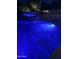 A blue glowing swimming pool with a raised hot tub, cascading waterfall feature, and manicured pavers at 6751 S Callaway Dr, Chandler, AZ 85249