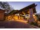 Elegant entrance with stone pillars, a wooden roof, and beautiful lighting at dusk at 6929 E Trailridge Cir, Mesa, AZ 85207