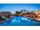 Evening shot of backyard pool includes a waterfall, slide, and lounge chairs for a relaxing ambiance after dusk at 6929 E Trailridge Cir, Mesa, AZ 85207