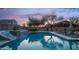 Backyard pool with lounge chairs, a slide, and a waterfall, illuminated by soft evening light creates a serene ambiance at 6929 E Trailridge Cir, Mesa, AZ 85207