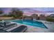 Backyard pool features a diving board, slide, lounge chairs for evening relaxation, set against a colorful sunset at 6929 E Trailridge Cir, Mesa, AZ 85207