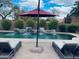 Relaxing poolside view with lounge chairs, a patio umbrella, and a waterfall feature adding to the tranquil setting at 8260 W Cielo Grande Ave, Peoria, AZ 85383