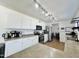 Open kitchen boasts white cabinets, modern appliances, and track lighting with a view to the dining area at 10563 E Bramble Ave, Mesa, AZ 85208