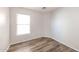 This bedroom offers modern plank floors, neutral walls, baseboards, an electrical outlet and a window at 12325 W Charter Oak Rd, El Mirage, AZ 85335