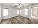 This bright bedroom features modern plank floors, neutral walls, baseboards, two shuttered windows, and a ceiling fan at 12325 W Charter Oak Rd, El Mirage, AZ 85335