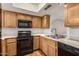 Well-lit kitchen features wood cabinets, a black oven and microwave, and stainless steel sink at 1328 S Mckemy St, Tempe, AZ 85281