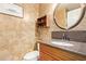 Elegant powder room with stone walls, a decorative mirror, and a stylish vanity at 1333 E Rockledge Rd, Phoenix, AZ 85048