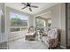 Bright sitting room featuring comfortable armchairs, a ceiling fan, and large windows showcasing verdant views at 1357 E Elysian Pass, Queen Creek, AZ 85140