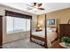 Cozy bedroom featuring a four-poster bed, ceiling fan and natural light from the window at 20148 N Big Dipper Dr, Maricopa, AZ 85138