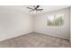 Empty bedroom with neutral walls and carpet, ceiling fan, and bright window offers a blank canvas at 2023 S 106Th Ave, Tolleson, AZ 85353