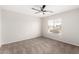 Empty bedroom features neutral carpeting and walls, ceiling fan, and bright window, offering a versatile space at 2023 S 106Th Ave, Tolleson, AZ 85353