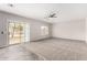 Bright living room featuring carpet, neutral walls, ceiling fan, and sliding glass door to backyard at 2023 S 106Th Ave, Tolleson, AZ 85353