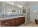 Bathroom featuring double sinks with decorative tile backsplash and a glass-enclosed shower at 20701 W Minnezona Ave, Buckeye, AZ 85396