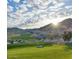 Picturesque view of a golf course with a mountain backdrop and sunny skies at 20701 W Minnezona Ave, Buckeye, AZ 85396