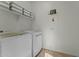 Modern laundry room with white front load washer and dryer and overhead shelving at 20701 W Minnezona Ave, Buckeye, AZ 85396