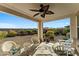 Relaxing covered patio features wicker furniture, a ceiling fan, and views of the desert landscaping at 20701 W Minnezona Ave, Buckeye, AZ 85396