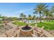 Beautiful pool area with a fire pit, lounge chairs, palm trees, and lush greenery at 20701 W Minnezona Ave, Buckeye, AZ 85396