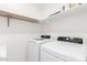 Bright laundry room with white washer and dryer plus storage shelves at 21295 E Estrella Rd, Queen Creek, AZ 85142