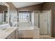 Bathroom featuring a large soaking tub, glass block window, and tiled shower at 3116 W Folgers Rd, Phoenix, AZ 85027