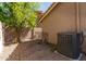 View of the side yard, with gravel, a tree, and an AC unit at 32 E Dawn Dr, Tempe, AZ 85284