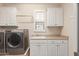 Well-lit laundry room features white cabinets, sink, and modern, front-load washer and dryer for convenient chores at 3234 N 163Rd Dr, Goodyear, AZ 85395