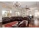 Expansive living room with dark wood floors, elegant chandeliers, and a comfortable leather sofa at 3234 N 163Rd Dr, Goodyear, AZ 85395