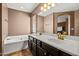 Bright bathroom with double sinks, a soaking tub, and earth-tone tile flooring at 3299 E Boston St, Gilbert, AZ 85295