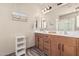 Bright bathroom with dual sinks, wood cabinets, and a glass-enclosed shower and neutral tones at 34969 N Open Range Dr, San Tan Valley, AZ 85144