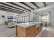 Open-concept kitchen with a large island, farmhouse sink, wood beam ceilings, and views into the living room at 35150 N Bell Rd, Queen Creek, AZ 85144