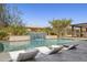 Backyard pool with a waterfall feature, surrounded by patio seating, lounge chairs, and mature landscaping at 5142 N 205Th Gln, Buckeye, AZ 85396