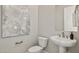 Well-lit powder room featuring a pedestal sink, toilet, and decorative artwork at 5142 N 205Th Gln, Buckeye, AZ 85396