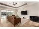 Bright living room with a brown leather sofa, black accents, wood flooring, and sliding glass doors leading to the pool at 5700 N 202Nd Ln, Litchfield Park, AZ 85340